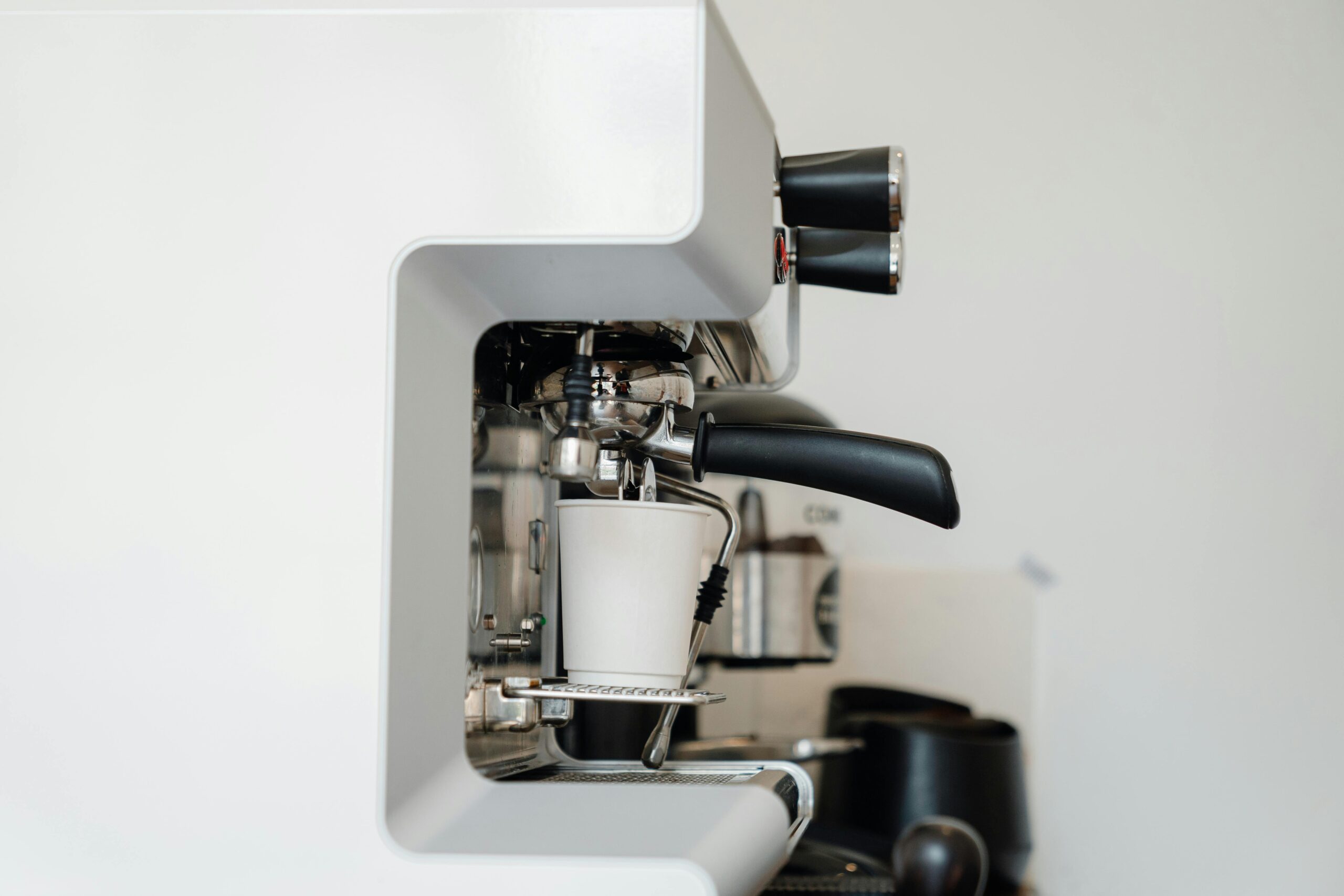 A sleek espresso machine brews a fresh cup of coffee in a minimalist kitchen setting.